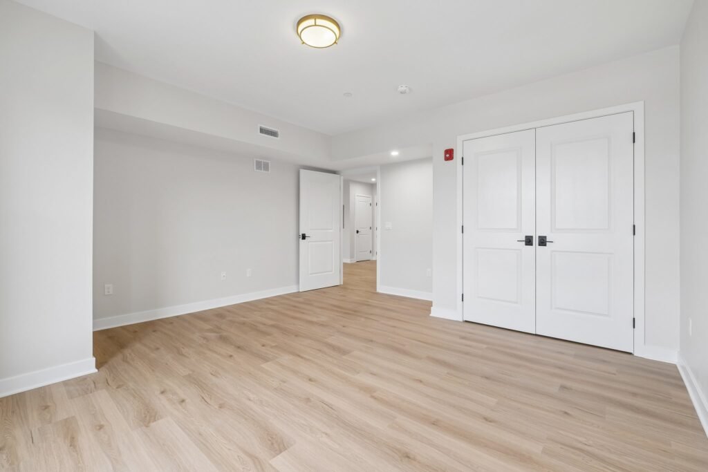 Bedroom with double-door closet and wide-plank flooring